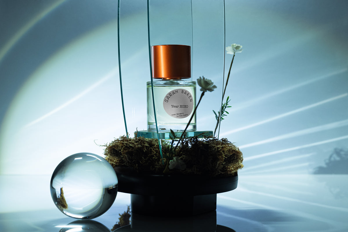 Sarah Baker Year XOXO perfume bottle in a blue-toned landscape scene