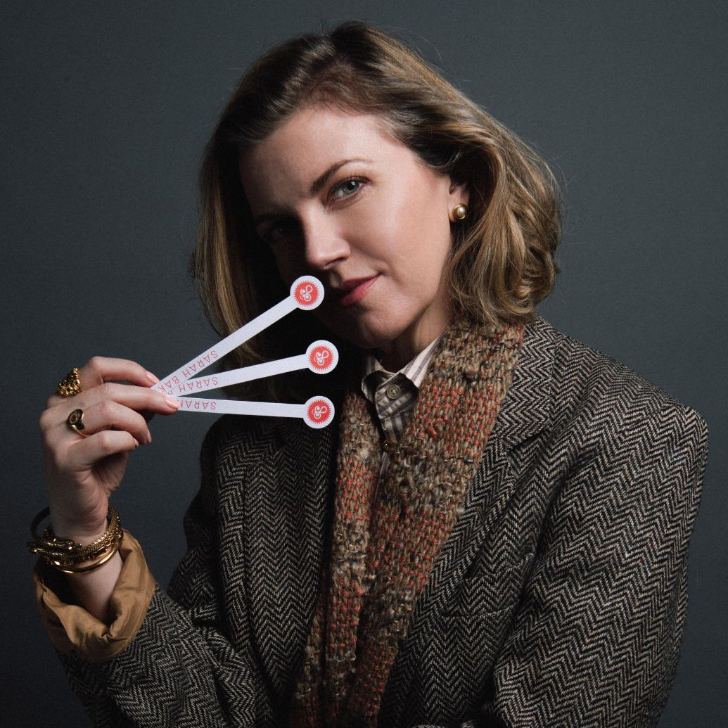 sarah baker holding three test strips against a dark background